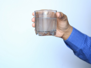 Man holding glass of dirty water affected by backflow contamination